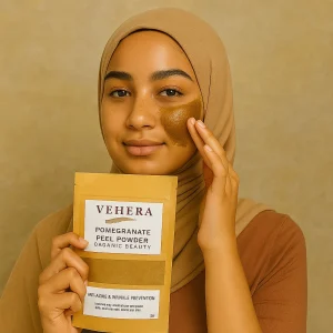 Young Muslim woman in beige hijab applying Vehera Pomegranate Peel Powder to her face for anti-aging skincare
